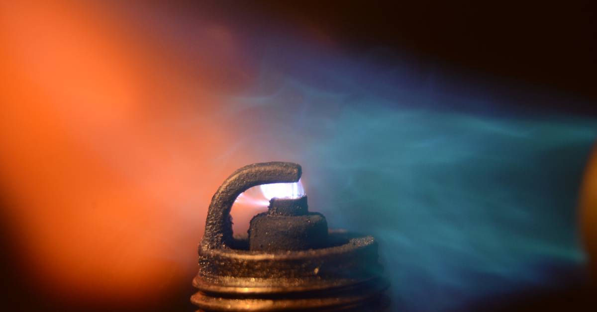 A spark plug ignition in a gas mixture process. The gas on the left appears orange, and the right appears blue.